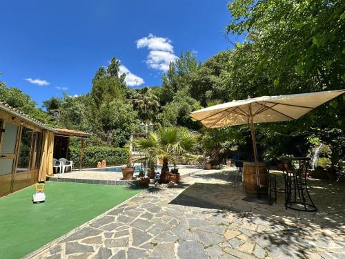 a patio with an umbrella and a green lawn at Vega Fuente de las Moreras in Burunchel