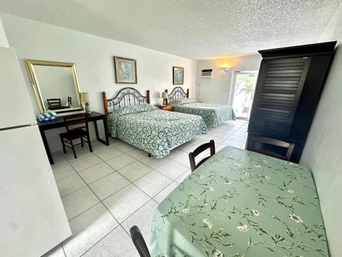 a room with two beds and a table and a desk at Birch Patio Motel in Fort Lauderdale