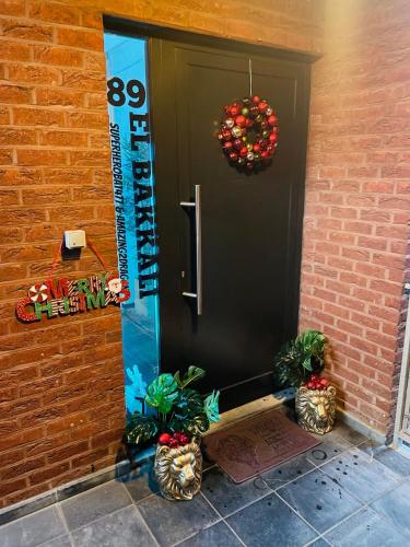 a black door with two potted plants and a wreath at Tommorowland Apartement in Boom