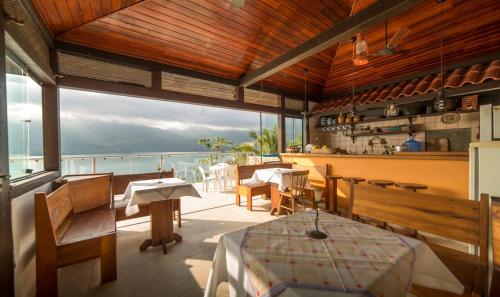 a dining room table and chairs in front of a large body of water at Pousada Victoria Reggia in São Sebastião