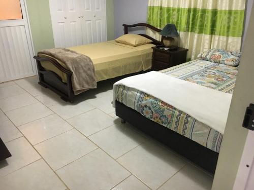 1 dormitorio con 2 camas y una lámpara en el suelo de baldosa en Posada Gordon Antonio, en San Andrés