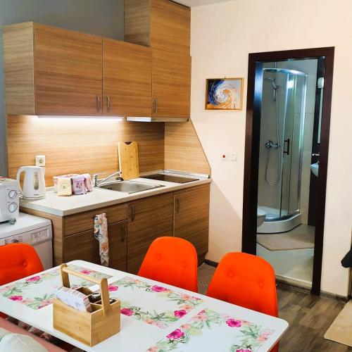 a kitchen with a table and orange chairs and a sink at Студио Стайл - Соренто Соле Маре in Sveti Vlas
