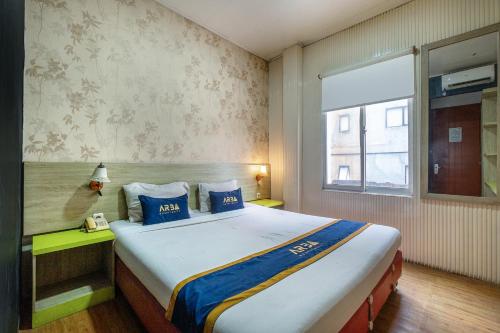 a bedroom with a large bed with blue pillows at Hotel Aleander By ARBA in Jakarta