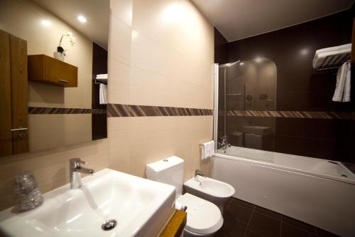a bathroom with a sink and a toilet and a tub at Hotel Rural Quinta da Conchada in Aguieira