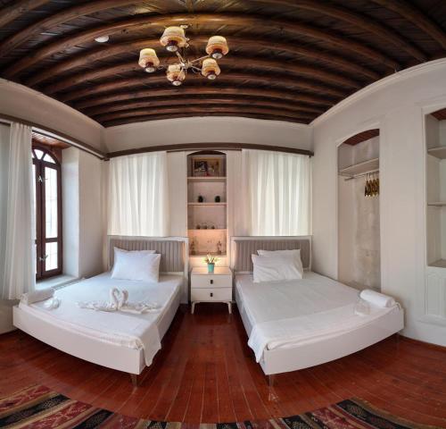 two beds in a room with a wooden ceiling at Gaziayintap Konağı in Şahinbey