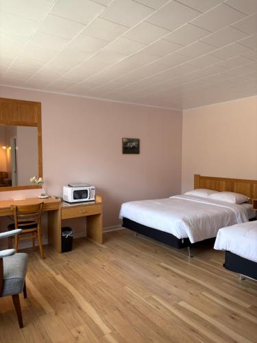 a room with two beds and a desk and a table at Le Délice Motel Restaurant in Mont-saint-pierre