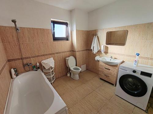 a bathroom with a tub and a sink and a washing machine at Virajlux Verde Retreat in Mioveni