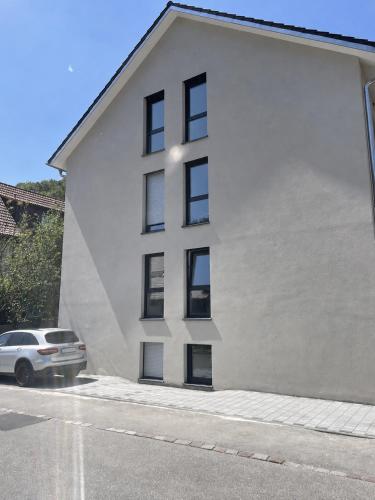 a white building with black windows on a street at M&S Apartments - Self Checkin in Degerfelden