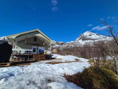 a house in the snow with a mountain in the background at Fjord & Flame in Tromsø