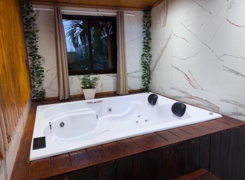 a bath tub in a bathroom with a window at Cabana com Hidro, Lareira e Piscina Privativa in Chapecó