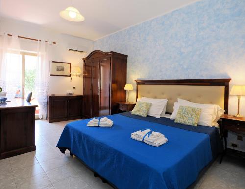 a bedroom with a blue bed with towels on it at Camere Santa Margherita in Santa Margherita-Sant'Alessio Siculo