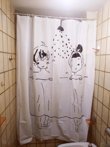 a bathroom with a shower curtain with drawings of people at Playa Velilla in Granada