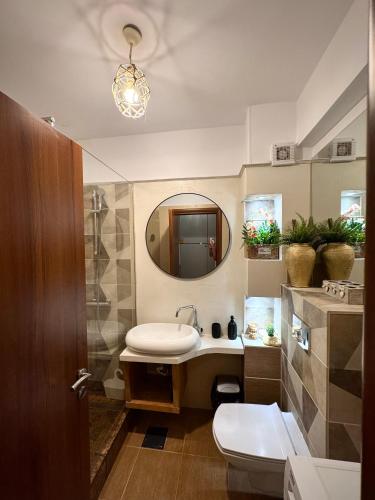 a bathroom with a sink and a mirror and a toilet at Arcadia Apartament Mamaia Nord in Mamaia Sat/Năvodari