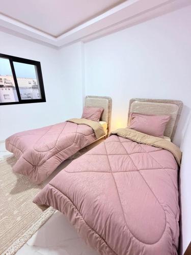 two beds sitting next to each other in a bedroom at Résidence jawhret el kram in El Aouina Station