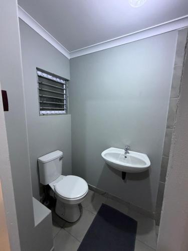 a white bathroom with a toilet and a sink at Amani Nest in Arcadia