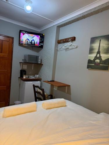 a bedroom with a bed and a tv on the wall at Amani Nest in Arcadia