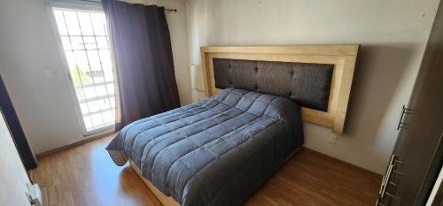 a bedroom with a bed with a wooden headboard and a window at Casa Misiones 1 in El Espino