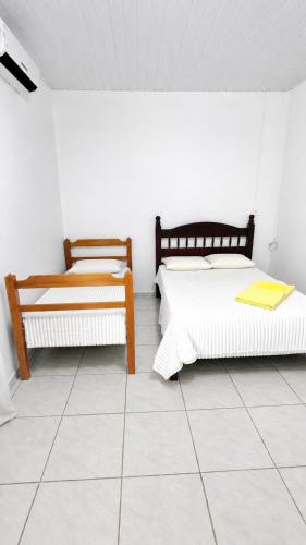 two beds in a room with a tiled floor at Estádia aconchegante! in Vilhena