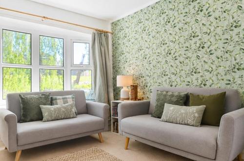 a living room with two chairs and a wall of wallpaper at Willow View Streamside Retreat near Kynren Durham in Newton Aycliffe