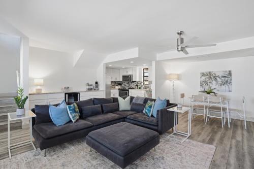a living room with a black couch and a kitchen at Be A Nomad - 3 Bedroom Apartment 1 Min to Jacksonville Beach - Sleeps 6 in Jacksonville Beach