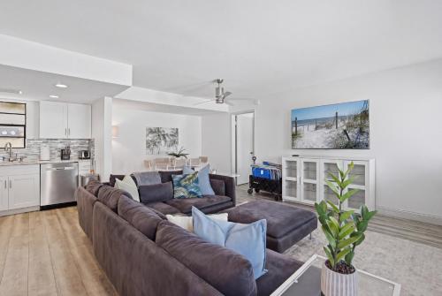 a living room with a brown couch and a kitchen at Be A Nomad - 3 Bedroom Apartment 1 Min to Jacksonville Beach - Sleeps 6 in Jacksonville Beach