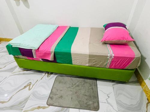 a bed with multicolored sheets sitting on the floor at Sunmoon Apartment in Deli