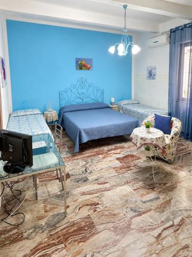 a bedroom with blue walls and a bed and a tv at B&B A Vinedda in Scilla