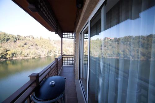 a room with a balcony with a view of a river at Hotel Rural Quinta da Conchada in Aguieira