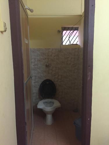 a bathroom with a toilet with a black seat at Nimmu Guest House & Restaurant Gokarna in Gokarna