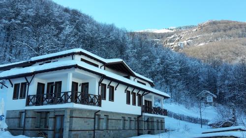 a house covered in snow in front of a mountain at Къща за гости ДАЯНИЦА in Kopilovtsi