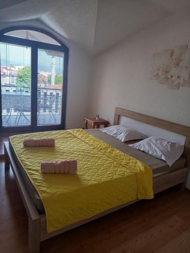 a bedroom with a bed with yellow sheets and a window at Apartments Mostrovi in Ohrid