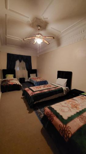 three beds in a room with a ceiling fan at Gite Tilouguite in Tillouguit nʼAït Isha