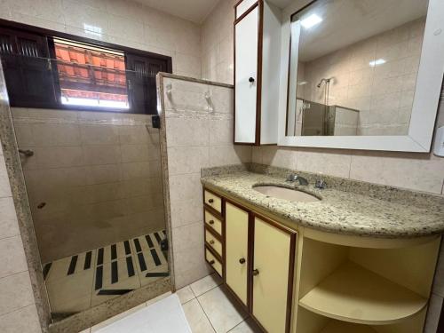 a bathroom with a sink and a shower with a mirror at Casa Bella Itaúna Suites in Saquarema