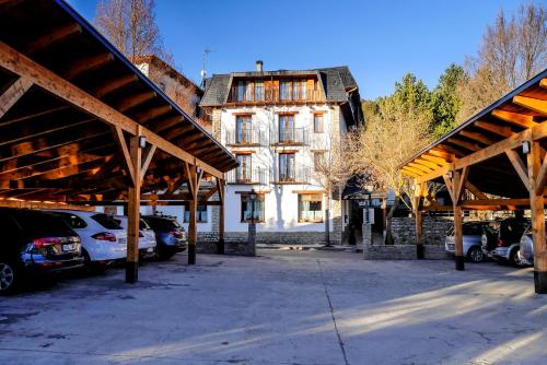 un grand bâtiment avec des voitures garées dans un parking dans l'établissement Hotel Esther, à La Virgen de la Vega