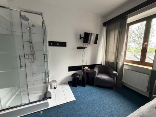 a bathroom with a shower and a chair and a glass showeroser at Hideout Villa in Hazlov