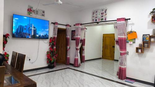 a room with curtains and a tv on a wall at Apex inn in Manippai