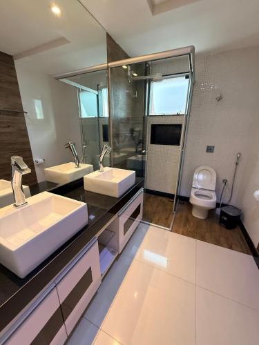 a bathroom with two sinks and a toilet at Apartamento 4 Quartos Completo UEMG Parque Expô in Divinópolis