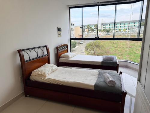 two beds in a room with a large window at Apartamento 4 Quartos Completo UEMG Parque Expô in Divinópolis
