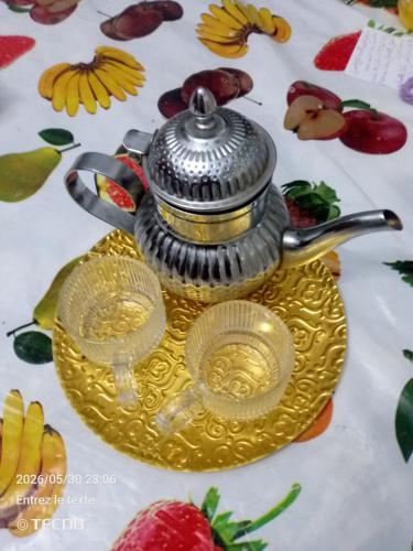 a tea pot on a gold plate with two plates at Dar MORTADA TATAOUINE in Tataouine