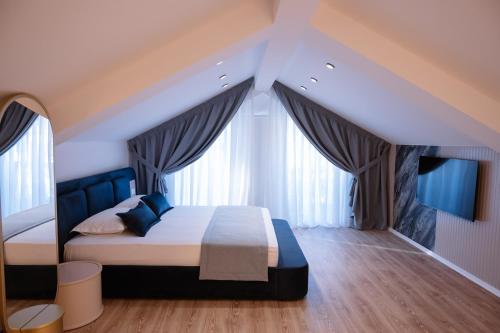 a bedroom with a bed with blue pillows and curtains at Villa 100 Boutique Pogradec in Pogradec