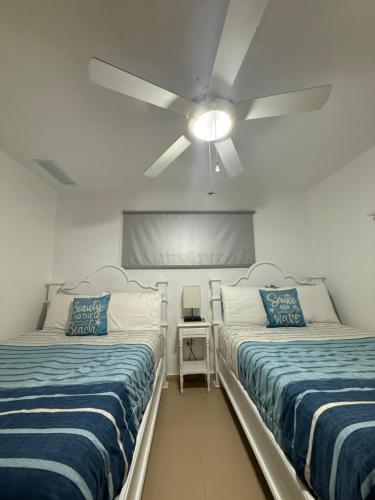 two beds in a room with a ceiling fan at Beach front Apt at Juan Dolio Marbella Apt Frente al mar 702 in San Pedro de Macorís