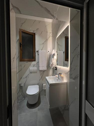 a white bathroom with a toilet and a sink at StayVibe in Krujë