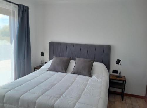 a bedroom with a large white bed and a window at Hostería Ayres del Lago in Los Antiguos