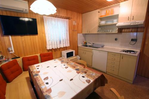 eine Küche mit einem Tisch und Stühlen sowie einem TV in der Unterkunft Čebelarjeva hiška - Terme Olimia - Podčetrtek in Podčetrtek