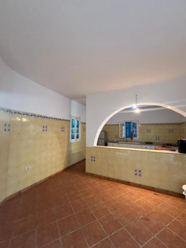 an empty gymnasium with an arch in a room at Villa sedghiani in El Guecheïne