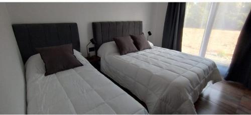 a bedroom with two beds and a window at Hostería Ayres del Lago in Los Antiguos