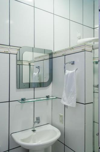a white bathroom with a sink and a mirror at Pousada do Mineiro in Trancoso