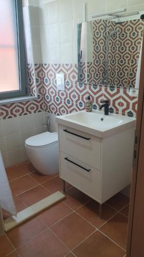a bathroom with a sink and a toilet and a mirror at Piccolo Paradiso Crotone in Casa Margherita