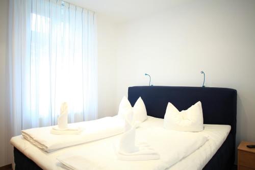 ein Schlafzimmer mit einem Bett mit weißen Kissen und einem Fenster in der Unterkunft Ferienwohnung Warnemünde L (S) in Warnemünde