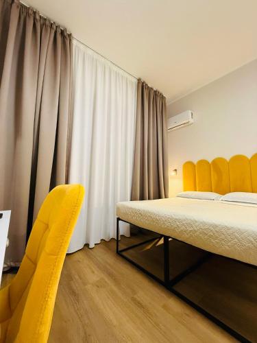 a bedroom with a bed and a yellow chair at Porta Amari B&B in Palermo